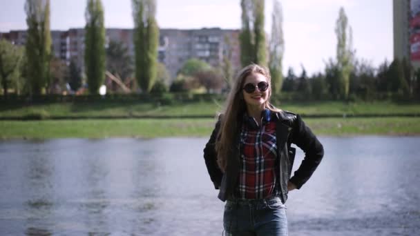 Casual tienermeisje in zonnebril genieten van het uitzicht in de buurt van de rivier in een zonnige dag — Stockvideo