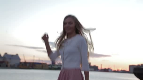 Mulher bebe cofee assistindo ao pôr do sol pulando e dançando porto fluvial — Vídeo de Stock
