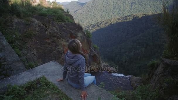 Ung kvinna som sitter på kanten av en rocky canyon ovanför floden bergen vietnam — Stockvideo