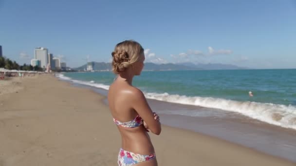 Prachtige jong meisje met een mooi figuur poseren en wandelingen langs de kust — Stockvideo