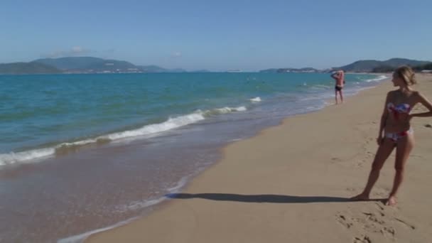 Hinreißende junge Mädchen mit einer schönen Figur posiert und geht entlang der Küste. High Five — Stockvideo