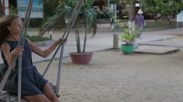 Junge Frau entspannt sich auf der Schaukel am Strand — Stockvideo