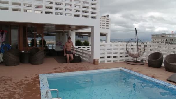 Homme sautant dans une piscine de luxe sur le toit . — Video