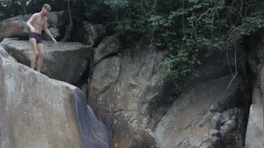 Genç adam su şelale kayaların üzerinden atlama