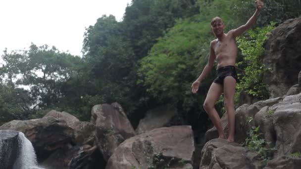 Jeune homme sautant des rochers de cascade dans l'eau — Video