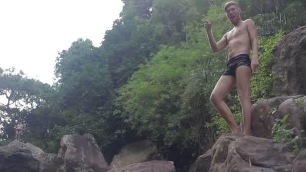 Jeune homme sautant des rochers de cascade dans l'eau — Video