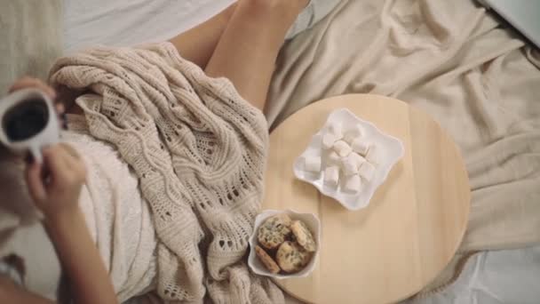 Kvinna i varm tröja på sängen med fika i händerna, julgran nyår upp punkt skytte — Stockvideo