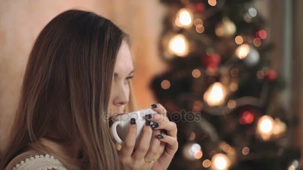 Kvinna i varm tröja på sängen med fika i händerna, julgran nyår närbild — Stockvideo