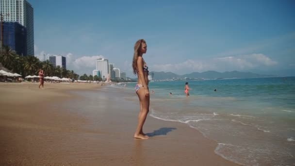 Prachtige jong meisje met een mooi figuur poseren en wandelingen langs de kust — Stockvideo