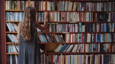 El kitap ile güzel genç kız raflardan yürür