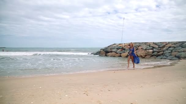 Vacker ung flicka med en vacker figur poserar och promenader längs havsstranden — Stockvideo