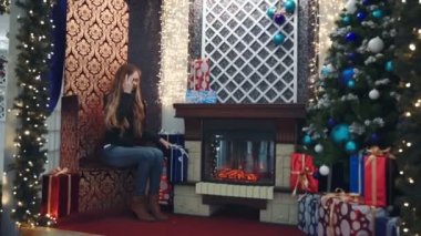 Şöminenin yanında genç bir kadın, Noel ağacı yakın bir sandalyede oturan kadın portresi oturan güzel kız