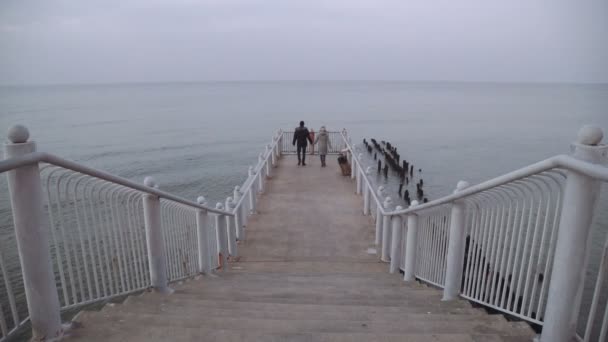 Par man och kvinna på piren titta på havet — Stockvideo