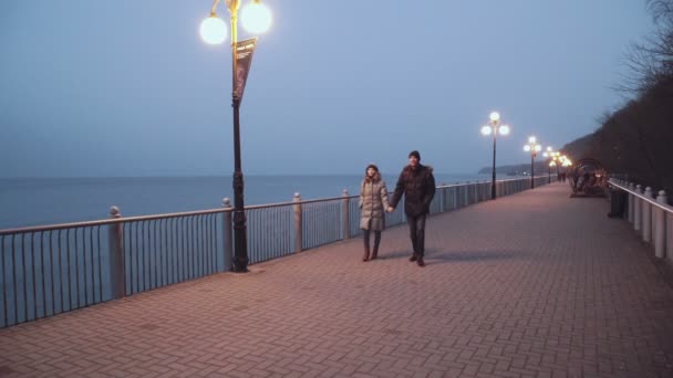 Casal homem e mulher caminham ao longo do passeio observando o mar — Vídeo de Stock