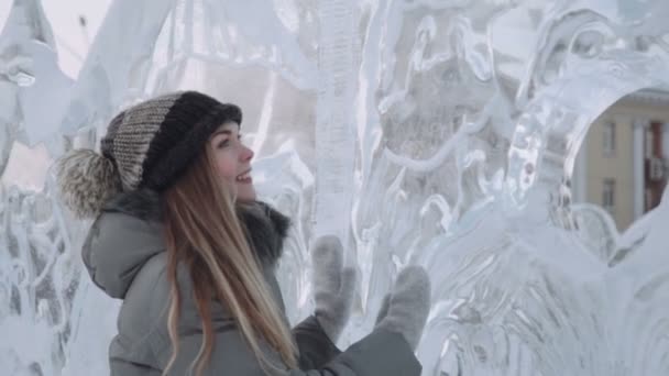 Young woman smiling at the ice sculptures, winter gloves — Stock Video