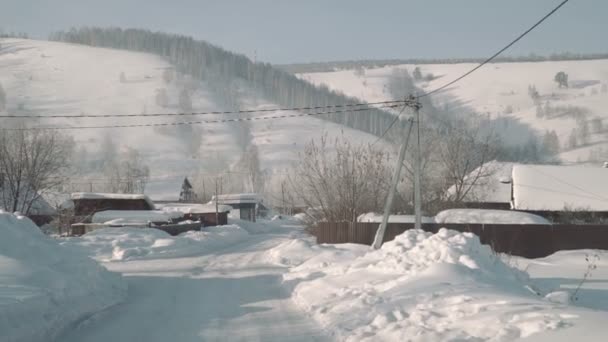 Hermoso pueblo de montaña en el día de invierno, casa tradicional y carretera cubierta de nieve pesada — Vídeos de Stock