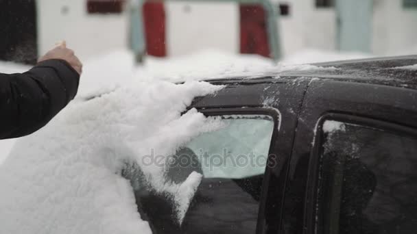 Transportation, winter, weather, people and vehicle concept - man cleaning snow from car with brush in living house district. — Stock Video