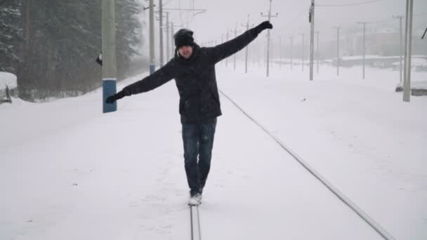 Retrato de un joven guapo con barba. Un hombre barbudo caminando por las vías del ferrocarril en invierno. Hombre barbudo joven sano en la naturaleza . — Vídeos de Stock