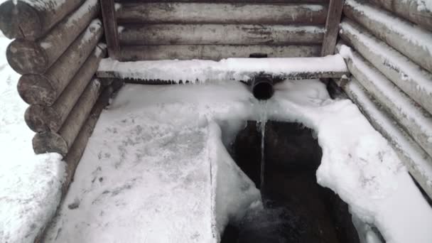 Trä kors, korsfästelsen nära upp nära trä väl på kyrka vinter, den kyrkan kyrkan gjort upp av trä stockar, landsbygdens vinterlandskapet, snö, — Stockvideo