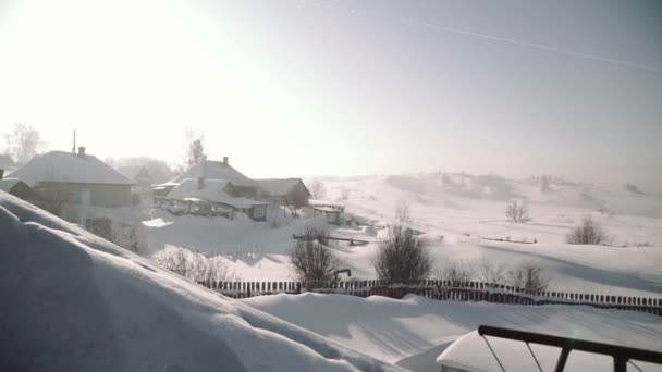 冬にシベリアの雪に覆われた森村で居心地の良い木造住宅の移動. — ストック動画