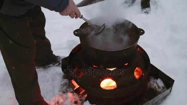 観光の人々 は冬に焚き火の火でぶら下がっている鍋で調理します。 — ストック動画