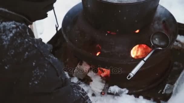 Tourist people cook in pot hanging over campfire fire in winter — Stock Video
