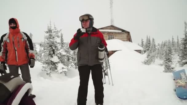 Skidåkare i hjälmen dricka te från termos. Utomhus vinter porträtt över snöiga bakgrund. Skidorten på berget — Stockvideo