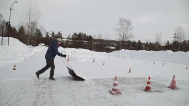siyah kürek kar beyaz kar temizler. adam temizler bir siyah kürek kar beyaz Autodrome kırmızı-beyaz yol konileri ile