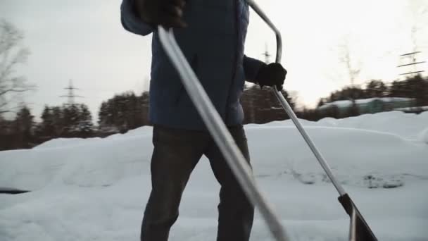 Siyah kürek kar beyaz kar temizler. adam temizler bir siyah kürek kar beyaz Autodrome kırmızı-beyaz yol konileri ile — Stok video