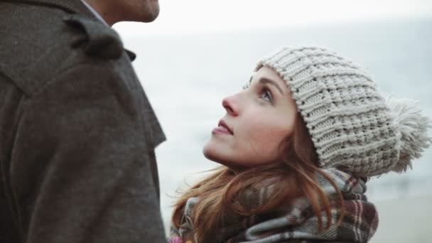 Casal jovem olhando para o mar, andando ao longo da praia, casaco e chapéu, Báltico ou Islândia tempo frio close-up — Vídeo de Stock