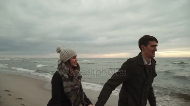 Junges Paar läuft am Strand am Meer, am Strand spazieren, Mantel und Hut, baltisches oder isländisches kaltes Wetter. 3-Achsen-Stabilisatorschuss — Stockvideo