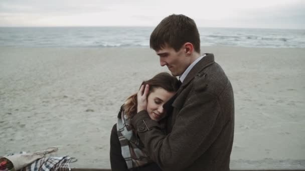 Casal jovem olhando para o mar, andando na praia, casaco e chapéu, Báltico ou Islândia tempo frio — Vídeo de Stock