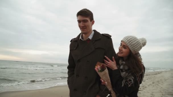 Pareja joven mirando al mar, caminando por la playa, abrigo y sombrero, clima frío del Báltico o Islandia — Vídeos de Stock