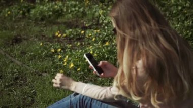 Güzel genç kadın mutlu bir yaz park güneşli ağaçların altında yemyeşil yeşil çim oturan kot pantolon