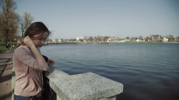 Mooie jongedame in het stadspark in de buurt van het meer — Stockvideo