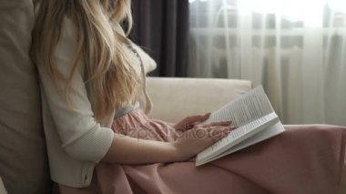 Kitap okuma ve gülümseyen koltukta oturan güzel genç kadın