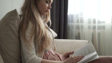 Kitap okuma ve gülümseyen koltukta oturan güzel genç kadın