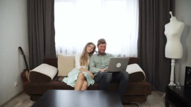 Çift laptop perde ve gülümseme göz evde kanepe kanepede oturuyor