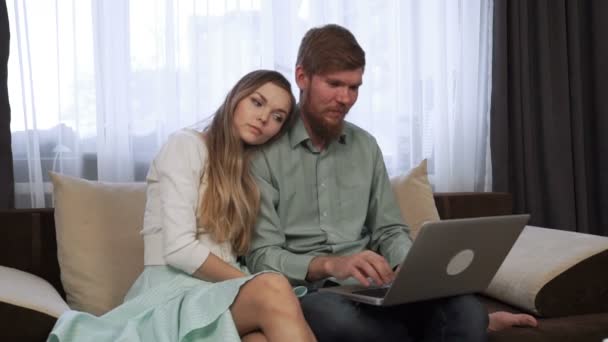 커플은 가정에서 소파 소파에 앉아 노트북 화면 및 미소 — 비디오