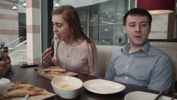 Junges Paar Frauen und ein Mann plaudern, trinken im Café des städtischen Cafés, — Stockvideo