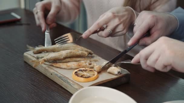 若いカップルの女性とチャット、男の飲み物を持つ市喫茶店カフェで話すし、打者で魚を食べる — ストック動画