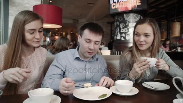 Glad grupp vänner två unga kvinnor och en man chattar, drycker i staden kafé café, — Stockvideo