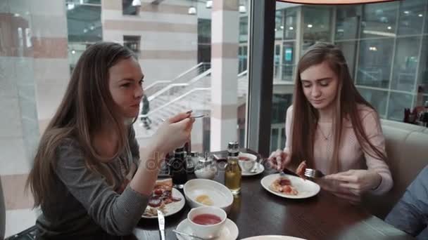 Amigos Dos mujeres jóvenes se conocieron en un café, almuerzo de negocios. Hablar y comer pizza italiana — Vídeo de stock
