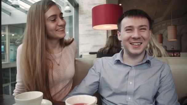Привлекательная молодая пара с помощью смартфона в кафе Посмотрите на дисплей улыбается — стоковое видео