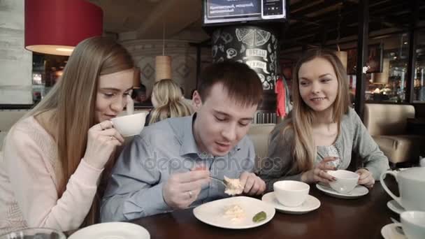 Счастливая компания друзей Две молодые женщины и мужчина болтают, выпивая в кафе городской кофейни , — стоковое видео