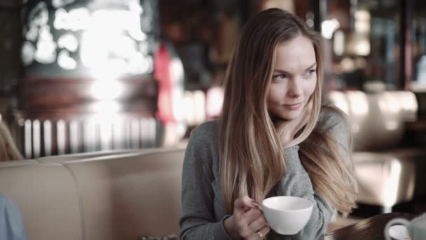 Ελκυστική γυναίκα πίνοντας καφέ ή τσάι στο καφενείο, steadicam πυροβόλησε — Αρχείο Βίντεο