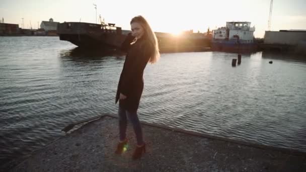 Mulher escovando o cabelo e dançando no porto do rio por do sol, brilho do sol na lente — Vídeo de Stock
