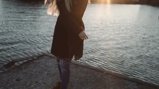Kvinna borsta håret och dans på sunset flod hamn, bländning från solen på linsen — Stockvideo