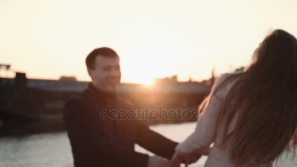 Attraktiva romantiska par tittar på båtarna i hamnen. i seaport, promenader och njuter av vacker solnedgång, Kyssar och kramar. — Stockvideo