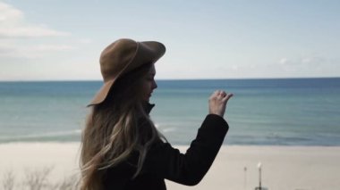 Bir elinde Smartphone ile yalnız kadın kış denizde görünüyor